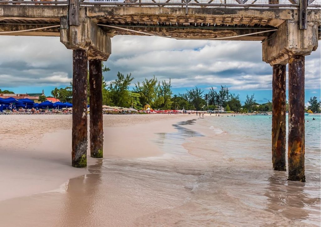 The photo was taken from under the pier at Boatyard Beach Club and you can see a white-sand beach and clear water with beach chairs in the background