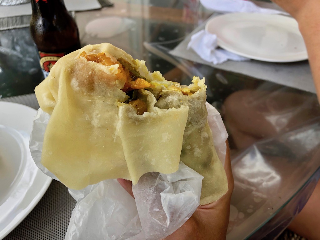 A roti wrap from De Roti Shop filled with vegetables. There's a bite taken out of the wrap