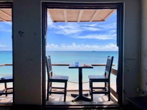 Two chairs and a table on a small balcony with a sea view at Surfers Cafe Barbados