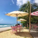 White and pink striped umbrellas over pink tables with a sea view at Baby Doll Restaurant Barbados