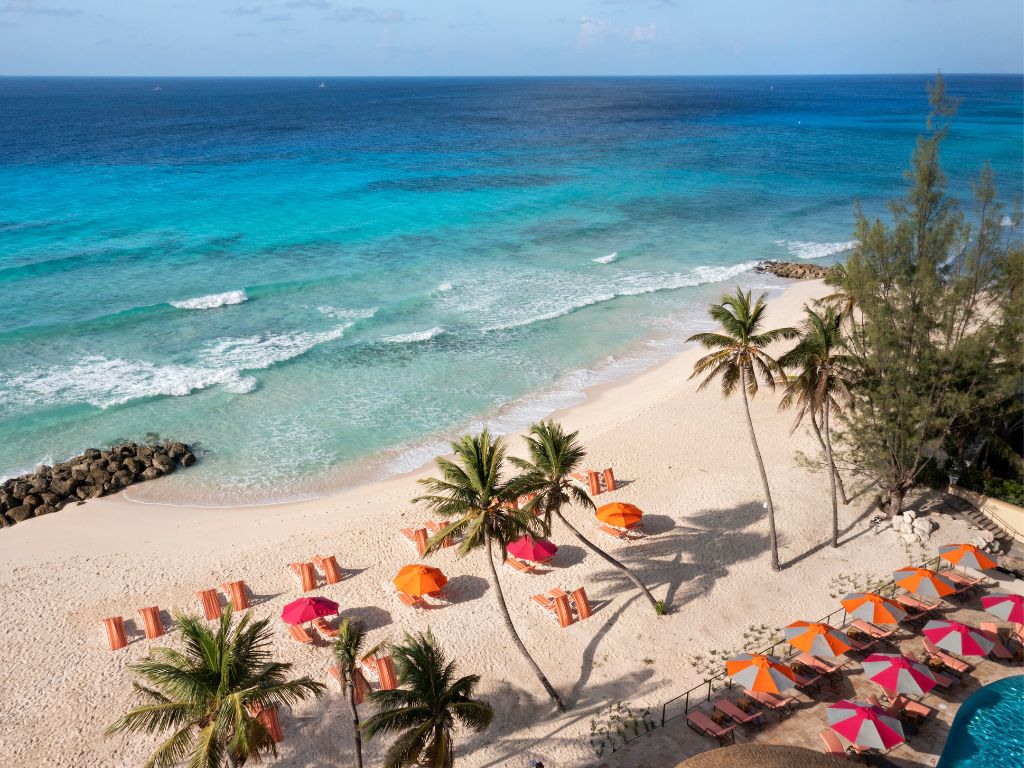 Orange and pink umbrellas on a white sand beach at O2 Beach Club and Spa Barbados